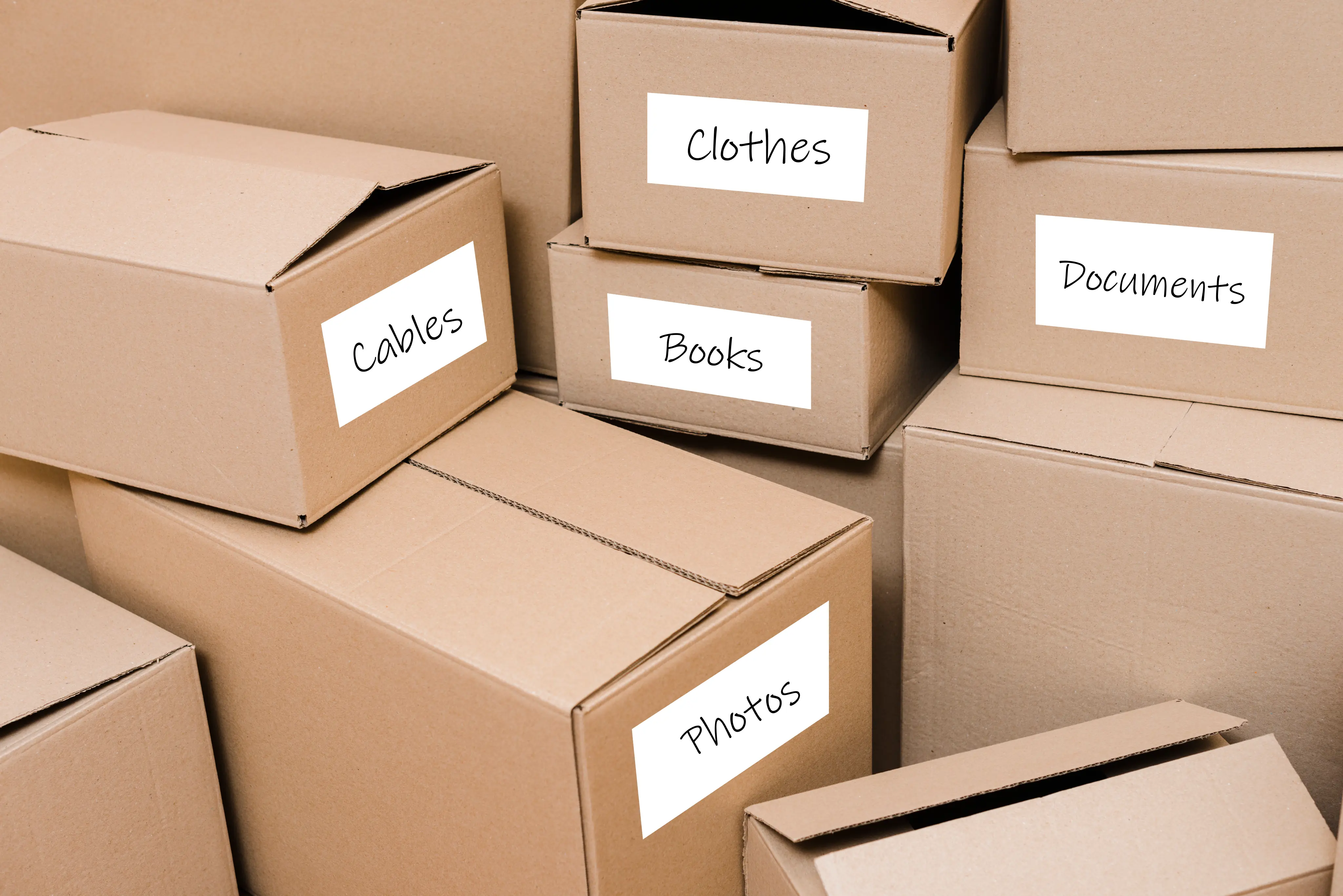 labelled cardboard boxes. On most of the boxes there is a label: cables, clothes, books, documents, photos
